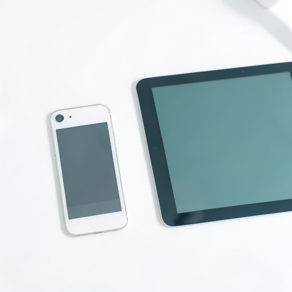 A minimalist desk setup with an iPhone and iPad side by side, clean white and muted teal tones